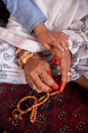 La mère d’Ehsanullah égrène ses perles de prière. Rare coquetterie autorisée : décorer ses doigts au henné pour la fête de l’Aïd-el-Kébir.