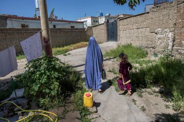 Sakinah, avec Safia, dans la cour de leur maison. Son mari lui a formellement interdit de montrer son visage à notre photographe.
